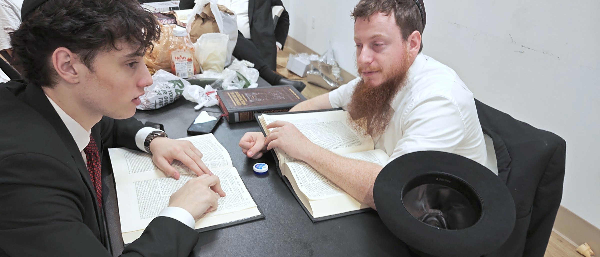 Chavrusa learning over an open Gemara — two students mid-argument